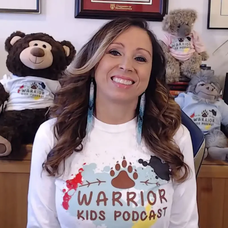 Pam smiling with her other animal plushies all wearing Warrior Kids Podcast shirts.